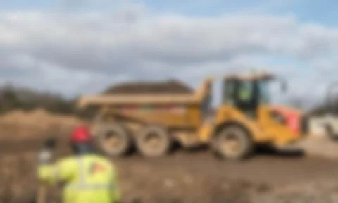 Defocused worker in high vis jacket and hard hat on a construction site Stock Photos