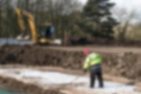 Defocused worker in high vis jacket and hard hat on a construction site Stock Photos