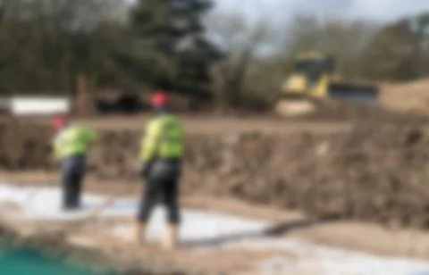 Defocused workers in high vis jackets on construction site Stock Photos