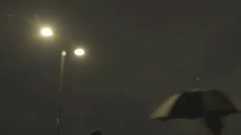 Defocussed view of commuters at night in the rain on london bridge Stock Footage 96486747