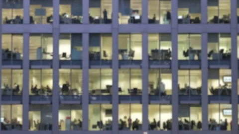 Defocussed view of people working overtime in an office at night Stock Footage 84480580