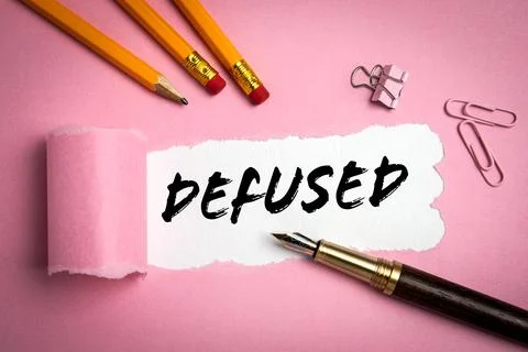 DEFUSED. Text under torn paper. Pencils and paper clips on a pink background Stock Photos