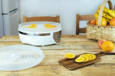 Dehydration machine with orange slices on kitchen table. Foto stock