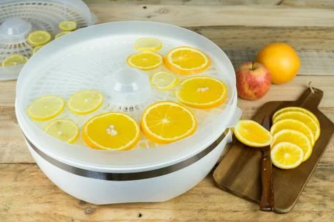 Dehydration machine with orange slices on kitchen table. Stock Photos