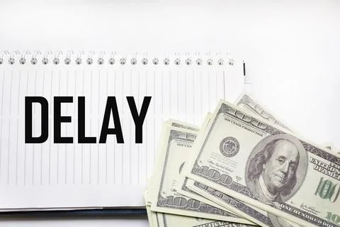 DELAY - word on a notepad with dollars in the background. Business concept Fotos de archivo