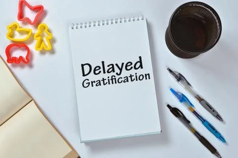 Delayed gartification text on notepad with office accessories. Business motiv Stock Photos