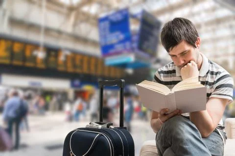 Delayed train concept. Passenger is sitting in train station, reading book an Stock Photos