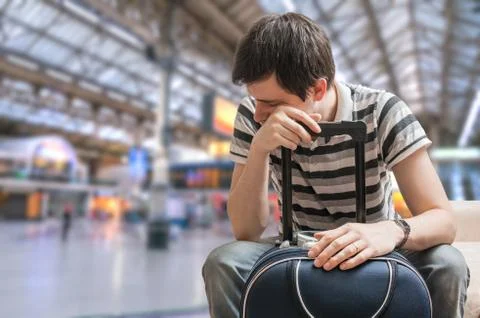 Delayed train concept. Tired passenger is sitting in train station and waitin Stock Photos