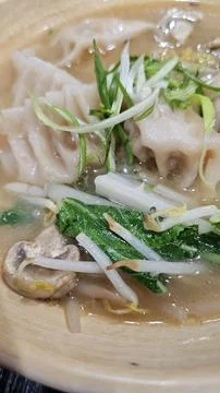 Delectable dumpling soup with fresh greens and mushrooms. Stock-Fotos