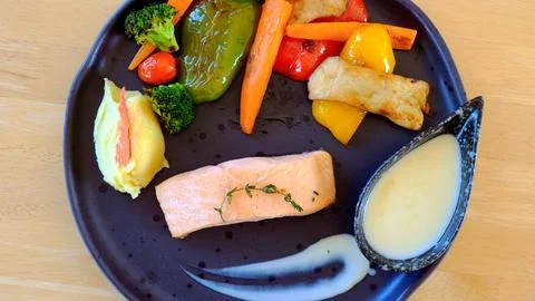 Delectable fried salmon steak with roasted potatoes and grilled vegetables Stock Photos