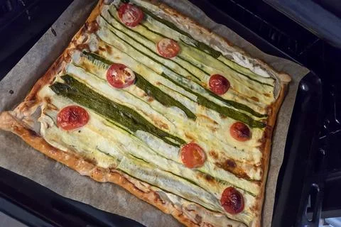 A delectable square tart featuring strips of zucchini and slices of tomato at Stock Photos