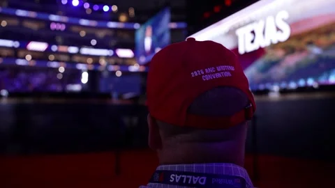 A delegate in a red cap watches a 'Texas' video on the screen, RNC Dallas 2026 Stock Footage 345271354