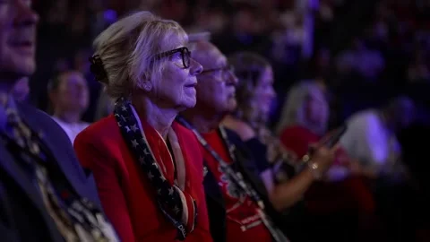 A delegate in a red jacket and flag scarf watches the stage, RNC Dallas 2026 Stock-Footage 345274164