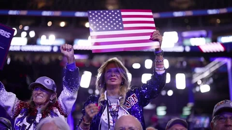 A delegate in a sequined jacket holds up an American flag placard Stock Footage 345274177