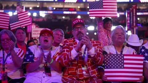 Delegates in a brick-wall-print suit and a 'Vote' cap applaud with American Stock Footage 345271477