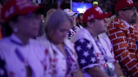 Delegates in stars-and-stripes shirts and red caps watch the speech Stock Footage 345274909