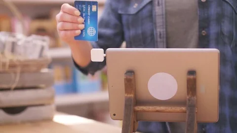 Deli owner using square chip reader connected to digital tablet Stock Footage