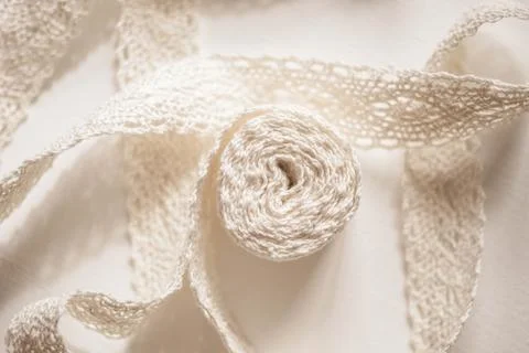 Delicate beige lace on a white table. Top view. Stock Photos