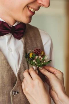 Delicate bride's hands adjust groom's boutonniere Stock Photos