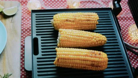 Delicate culinary study: grilling whole corn until golden Stock Photos