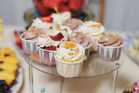 Delicate cupcakes rest on a clear two-tier stand Fotos de archivo