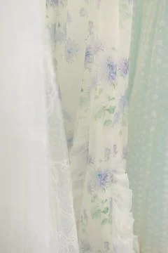 Delicate fabrics and patterns hanging in soft lighting at a boutique clothing Foto stock