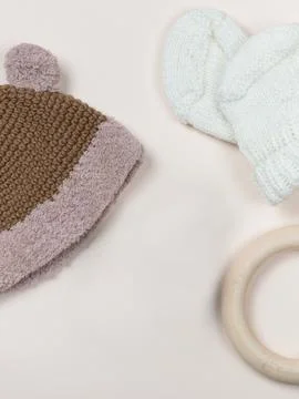 A delicate flat on a beige background with a knitted cap and booties for a baby Stock Photos