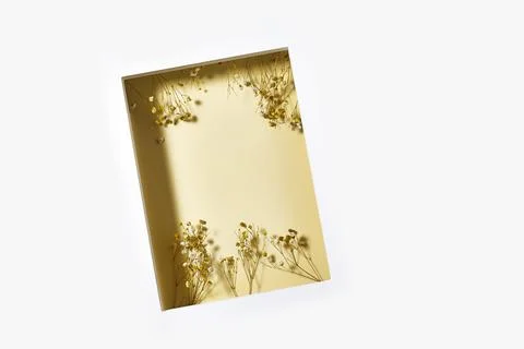 Delicate frame tilted on a white surface holds dried flowers along the edges, cr Stock Photos