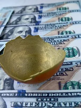 A delicate golden eggshell rests on a surface surrounded by numerous hundred Foto stock