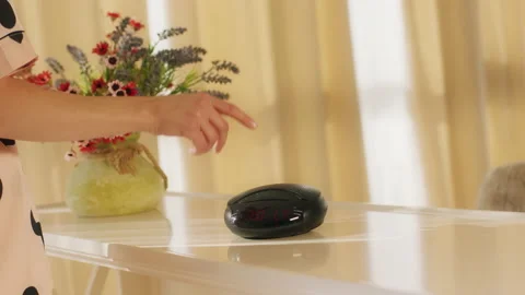 A delicate hand turns on a black speaker which is sitting on top of a smooth and Stock Footage 164838308