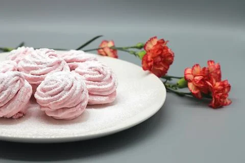 Delicate handmade marshmallows on a white plate with flowers on a gray backgr Stock Photos