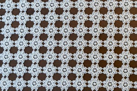 Delicate lace pattern on a wooden table. The intricate design features floral Stock Photos