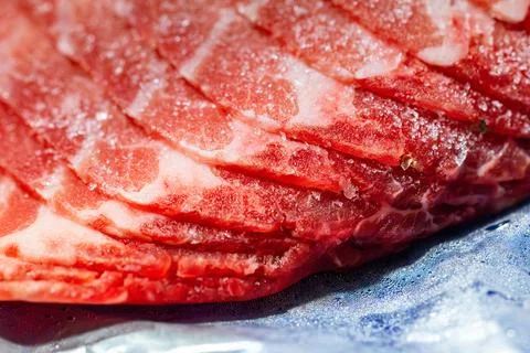 The delicate marbled texture of bright red frozen pork slices 스톡 사진