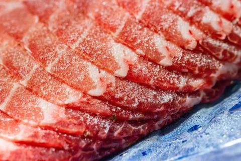 The delicate marbled texture of bright red frozen pork slices Stock Photos