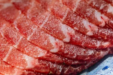The delicate marbled texture of bright red frozen pork slices Stock Photos