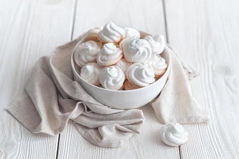 Delicate meringues on a white background with a cup of tea. Side view.Airy me Stock Photos
