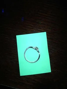 A delicate silver ring resting on a vibrant turquoise note against a dark w.. Stock Photos