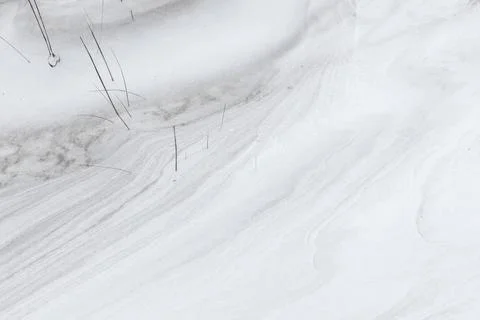 Delicate snow drift patterns and thin grass stems create a minimalist winte.. Stock Photos