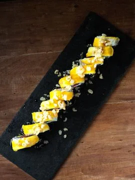 Delicate sushi rolls sit elegantly on a dark slate Stock Photos