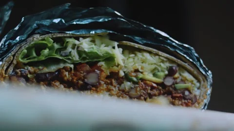 Delicate tabletop view: halved burrito revealing beef and vegetables Video stock 342174918