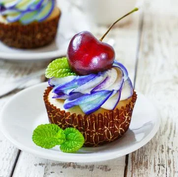 Delicate vanilla cupcakes with cream and berries on a white wooden background Stock Photos