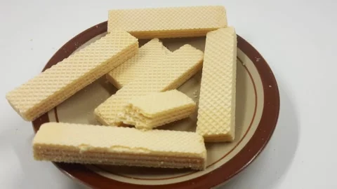 Delicate vanilla wafer biscuits subtly shifting on a rustic brown plate footage Stock Footage 330336028