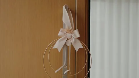 Delicate white bow with a floral accent decorates a wooden door handle, Vidéo 285012265