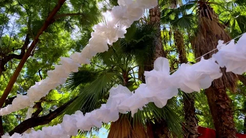 Delicate white decorations sway gently under a vibrant blue sky Video stock 289541974