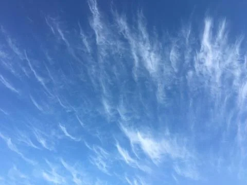 Delicate white feather clouds on the blue sky. Stock Photos