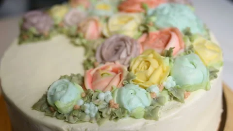 A delicate white wedding cake is decorated with a wreath of edible roses in past Stock Footage 143743987