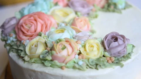 Delicate white wedding cake with a wreath of edible roses in pastel colors. Beau Stock Footage 143744196