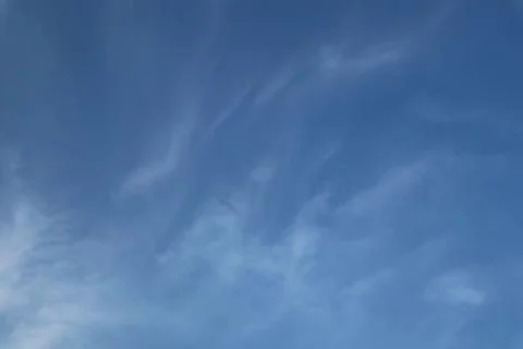 Delicate wisps of cirrus clouds floating across a deep blue sky Stock Photos