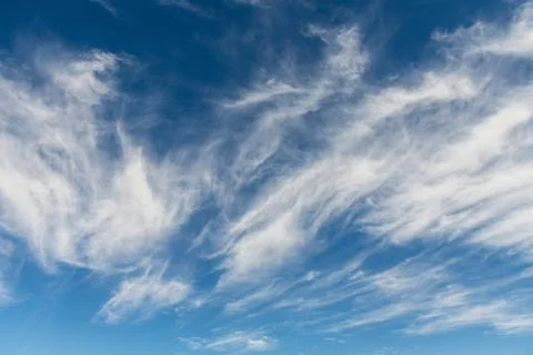 Delicate wispy cirrus clouds stretch diagonally across a deep blue sky, cre.. Stock Photos