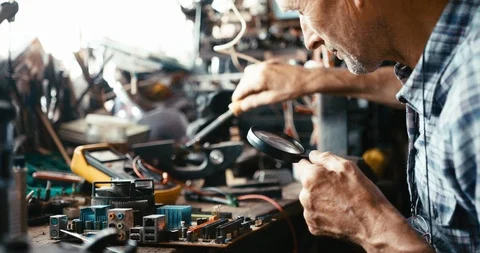 Delicate work of old technician soldering using the soldering iron and the Stock Footage 93137891